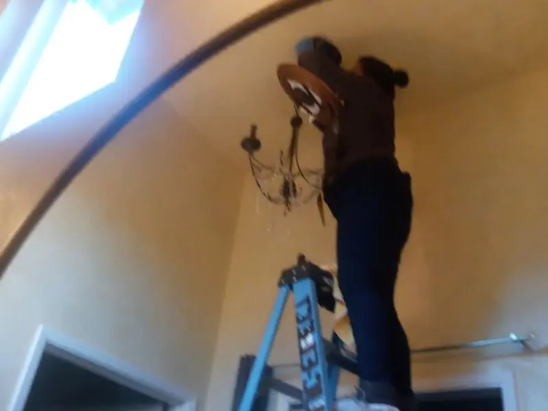 Electrician installing a chandelier in a Rockland residence